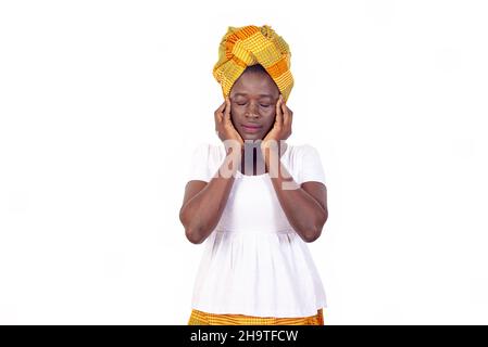 Schöne junge afrikanische Frau in traditionellem Kleid auf weißem Hintergrund stehend und Kopfschmerzen fühlend. Stockfoto