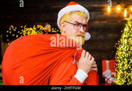 Weihnachtsmann trägt große Tasche mit Geschenken. Frohe Weihnachten und Frohes neues Jahr. Weihnachtsgeschenke. Stockfoto