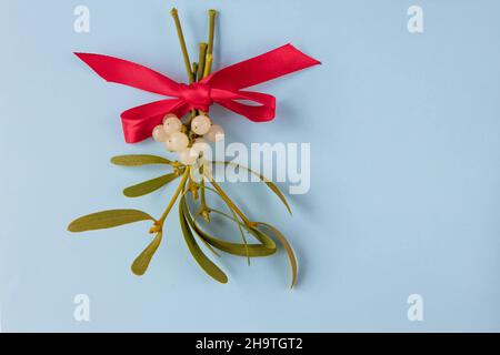 Rote Schleife auf einem Mistelhaufen mit weißen Beeren und grünen Blättern gebunden. Weihnachtsdekoration. Stockfoto