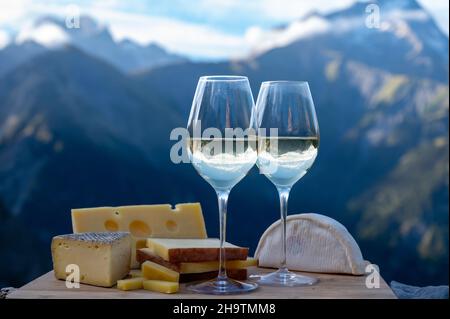 Schmackhafter Käse und Wein aus Savoyen in Frankreich, beaufort, abondance, emmental, Tomme und Reblochon de savoie Käse und ein Glas Weißwein serviert Stockfoto