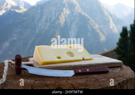 Käsesammlung, französischer emmental de savoie Käse mit runden Löchern, serviert im Freien in der Savoyer Region, mit Berggipfeln im Sommer auf dem Backgrou Stockfoto
