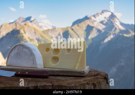 Käsesammlung, französisches Reblochon und emmental de savoie Gratin serviert im Freien mit Berggipfeln im Sommer im Hintergrund Stockfoto