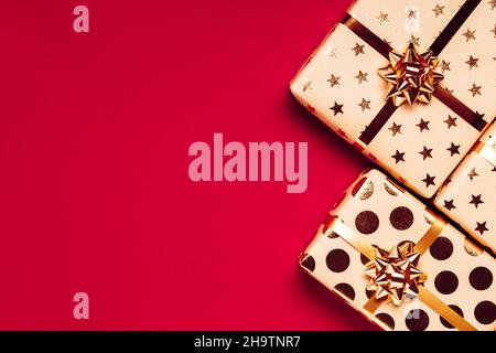Geschenkboxen mit goldenen Schleifen auf rotem Hintergrund. Stockfoto