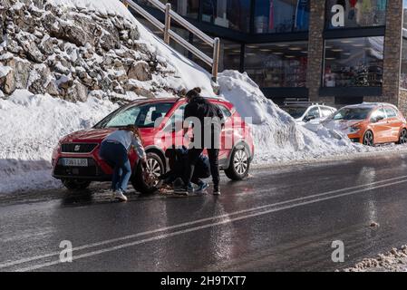 Canillo, Andorra: 2021. Dezember 8: An einem verschneiten Tag in Andorra in den Pyrenäen legen die Menschen Ketten auf ihre Räder. Stockfoto