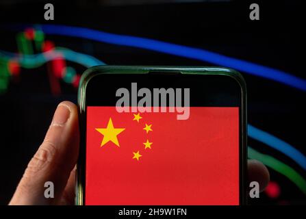 China. 4th Dez 2021. In dieser Fototafel wird die Flagge der Volksrepublik China auf einem Smartphone mit einem wirtschaftlichen Börsenindex im Hintergrund angezeigt. (Bild: © Chukrut Budrul/SOPA Images via ZUMA Press Wire) Stockfoto