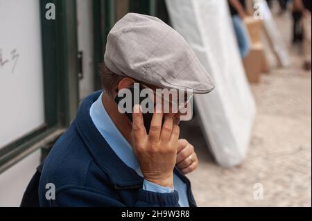 '11.06.2018, Portugal, , Lissabon - ein älterer Mann in einem Schlampenhut spricht auf seinem Handy in der portugiesischen Hauptstadt. 0SL180611D049CAROEX.JPG [MODELL RE Stockfoto