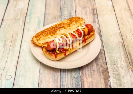 Klassischer Hot Dog mit Senf, Ketchup und Mayonnaise auf geröstetem Brioche-Brot Stockfoto