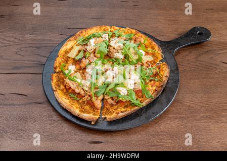 Exotisches Pizzarezept mit Ananas, Rucola, Ziegenkäse und gebratenem Huhn Stockfoto