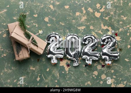 Silberne Luftballons in Form von Figur 2022 und Weihnachtsgeschenke auf farbigem Hintergrund Stockfoto