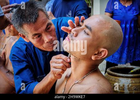 Ein Mann lässt seinen Kopf schütteln, bevor er ein buddhistischer Mönch in Nakhon Nayok, Thailand, wird. Stockfoto