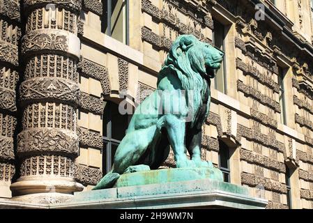 Bronzelöwenskulptur mit verwitterter grüner Verdigris patina steht an einem sonnigen Tag am Porte des Lions vor dem Louvre in Paris, Frankreich. Stockfoto