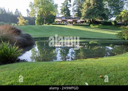 Taupo Neuseeland - 27 2021. November: Das Morgenlicht reflektiert die Gebäude der Lodge in einem ruhigen Teich auf einem wunderschön angelegten Gelände. Stockfoto