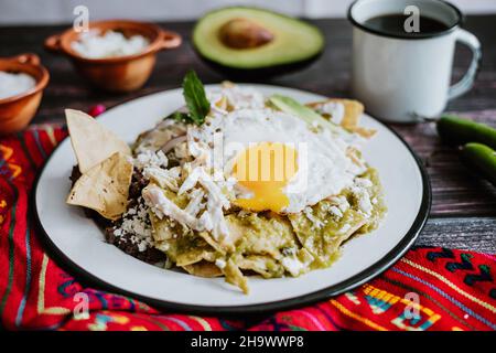 Mexikanische grüne Chilaquiles mit Spiegelei, Huhn und würziger grüner Sauce traditionelles Frühstück in Mexiko Stockfoto