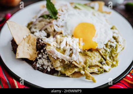 Mexikanische grüne Chilaquiles mit Spiegelei, Huhn und würziger grüner Sauce traditionelles Frühstück in Mexiko Stockfoto