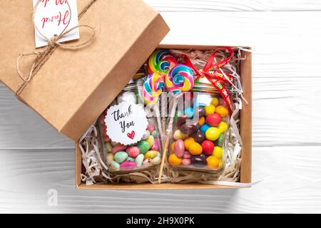 Handgemachtes Pflegepaket, saisonale Geschenkbox mit Süßigkeiten, Tasse auf weißem Tisch Personalisierter umweltfreundlicher Korb für Familie, Freunde, Mädchen für Danksagedanken Stockfoto