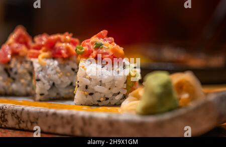 Makro-Sushi-Rolle von würzigem rohem Thunfisch auf einem schönen Steinteller, gesundes japanisches Essen, Sushi-Rolle mit weicher Fokussierung in dunkler Stimmung. Stockfoto