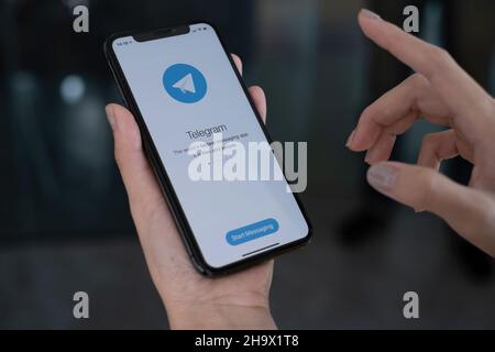 CHIANG MAI, THAILAND, DEC 09, 2021 : Frau Hand hält iPhone X mit Social-Networking-Service Telegram auf dem Bildschirm. IPhone 10 wurde erstellt und Stockfoto