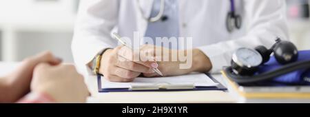 Arzt sitzt am Tisch und bereitet medizinische Aufzeichnungen mit Kugelschreiber Nahaufnahme Stockfoto