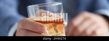 Mann im Anzug, der ein Glas Whiskey mit Eis in der Hand hält Stockfoto