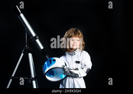 Kleines Kind will einen im Weltraum fliegen, Junge mit Teleskop trägt einen Astronautenhelm. Speicherplatz kopieren. Erfolg, Kreativität und Start-up-Konzept. Stockfoto