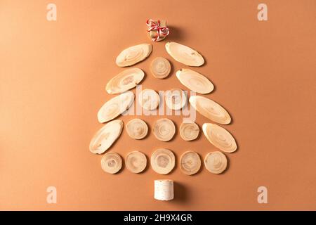 Weihnachtsbaum aus Baumschnitten mit einem kleinen Geschenk auf der Oberseite. Kreatives Öko-Konzept für Weihnachtskarte. Stockfoto