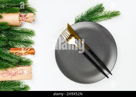 Ansicht des weißen Weihnachtstisches mit festlichen Gerichten mit Rahmen von Dekorationen aus Fichtenzweigen und Geschenken Stockfoto