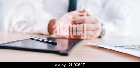 Eingabestift und Pad mit E-Signatur auf dem Büroschreibtisch, Hände eines Geschäftsmannes im Hintergrund, Panoramabild mit selektivem Fokus Stockfoto