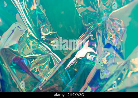 Mintfarbener, schillernder holographischer Hintergrund. Zerknittert Folienoberfläche. Defokussierte abstrakte Hintergrundkulisse. Stockfoto