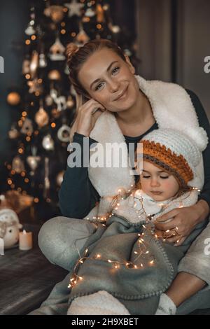 Liebende Mutter genießt Weihnachten mit ihrem schönen Baby. Glückliche Familie Dekorieren Haus für Winterferien Feiern. Vorbereitung auf Weihnachten. Frohes neues Jahr. Stockfoto