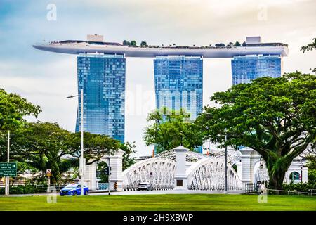 Die Anderson Bridge ist eine fußgängerfreundliche Brücke aus dem Jahr 1910, die einen malerischen Blick auf den Fluss mit ihren markanten weißen Metallarbeiten bietet. Mit Marina Bay Sands im Hintergrund. Stockfoto