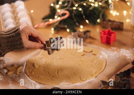 Frau, die zu Hause Lebkuchen macht. Weibliche Schneide Kekse aus Lebkuchenteig, Blick von oben. Draufsicht der Frau mit Herstellung Gingerbrean sternförmig Stockfoto