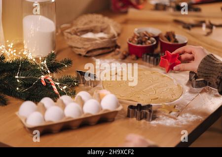 Frau, die zu Hause Lebkuchen macht. Weibliche Schneide Kekse aus Lebkuchenteig, Blick von oben. Draufsicht der Frau mit Herstellung Gingerbrean sternförmig Stockfoto