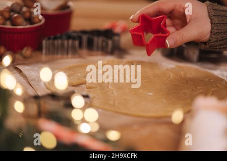 Frau, die zu Hause Lebkuchen macht. Weibliche Schneide Kekse aus Lebkuchenteig, Blick von oben. Draufsicht der Frau mit Herstellung Gingerbrean sternförmig Stockfoto