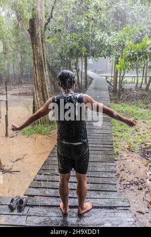 KINABATANGAN, MALAYSIA - 21. FEBRUAR 2018: Mann nimmt im Uncle Tan Wildlife Camp in der Nähe des Kinabatangan-Flusses, Sabah, Ma, einen Outdoor-Whower im Regen Stockfoto