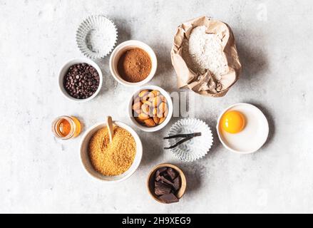 Kochen flache Lay von verschiedenen Lebensmitteln Zutaten zum Backen auf grauem Hintergrund. . Set aus verschiedenen Backzutaten - Mehl, Eier, Honig, Schokolade, Nüsse Stockfoto
