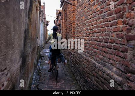 Zwei Schwestern fahren Fahrräder und tragen sich in einer kleinen Gasse im Dorf Tho Ha, Bac Giang, Vietnam Stockfoto