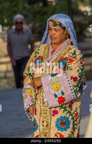 BUKHARA, USBEKISTAN - 30. APRIL 2018: Einheimische Frau in traditioneller Kleidung im Zentrum von Bukhara, Usbekistan Stockfoto