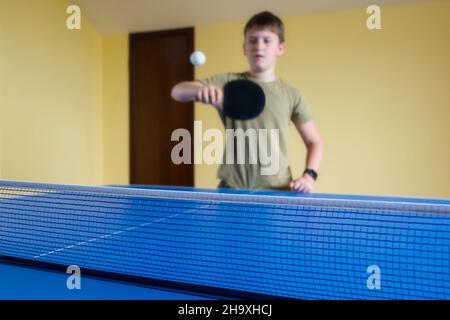 Netter Junge, der drinnen Tischtennis spielt. Tischtennis. Stockfoto