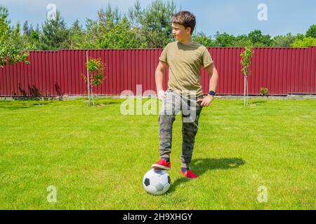 Ein Junge mit einem Ball im Hinterhof an einem sonnigen Sommertag. Sportspiele. Gesundes Lifestyle-Konzept Stockfoto