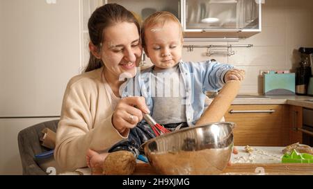 Kleiner Junge, der Mutter beim Kneten von Teig und beim Backen von Brot in der Küche half. Konzept des kleinen Küchenchefs, Kinder kochen Essen Stockfoto