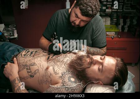 Tattoo-Meister macht Tattoo-Bilder in seinem Salon Stockfoto