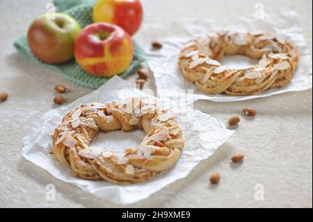 Mit Äpfeln und Mandeln gefüllte und mit Puderzucker bestäubte Gebäckkränze (vegan) Stockfoto