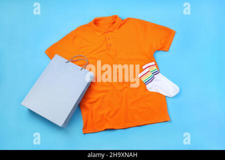 Leeres T-Shirt, Tasche und Socken auf blauem Hintergrund Stockfoto