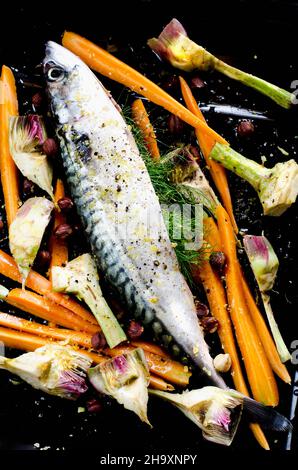 Makrelen mit Karotten und Artischocken auf einem Backblech Stockfoto