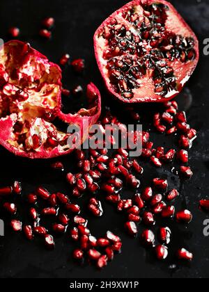 Ein halbierte Granatapfel und Granatapfelkerne auf einer Holzoberfläche Stockfoto