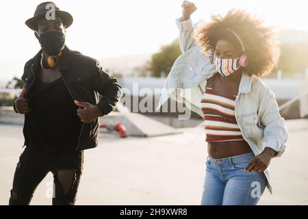 Afrikanische Menschen tanzen tragen Sicherheitsmasken im Freien Musik hören - Weiche Fokus auf Mädchen Gesicht Stockfoto