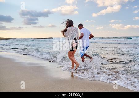 Glückliches Paar, das am Sommertag am Strand zusammen läuft, Rückansicht Stockfoto