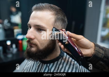 Der Meister im Friseurladen macht das Haarschneiden von Männern mit Haarschneider Stockfoto