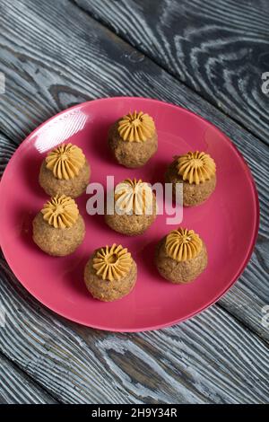 Bananenkuchen mit Buttercreme. Auf einen Teller legen. Auf schwarzen Kiefernbrettern. Nahaufnahme. Stockfoto