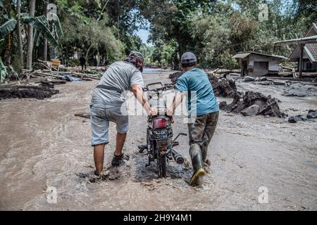 Kamar Kajang, Indonesien. 09th Dez 2021. Dorfbewohner evakuieren ein Motorrad, das nach dem Ausbruch des Berges Semeru in Kamar Kajang, Lumajang, von der kalten Lava begraben wurde. Mindestens 14 Menschen sind tot und Dutzende werden verletzt, nachdem Mount Semeru, ein Vulkan in der indonesischen Provinz Ost-Java, am Samstag ausbrach und Aschetürme und heiße Wolken warf, die nahe gelegene Dörfer bedeckten. Kredit: SOPA Images Limited/Alamy Live Nachrichten Stockfoto